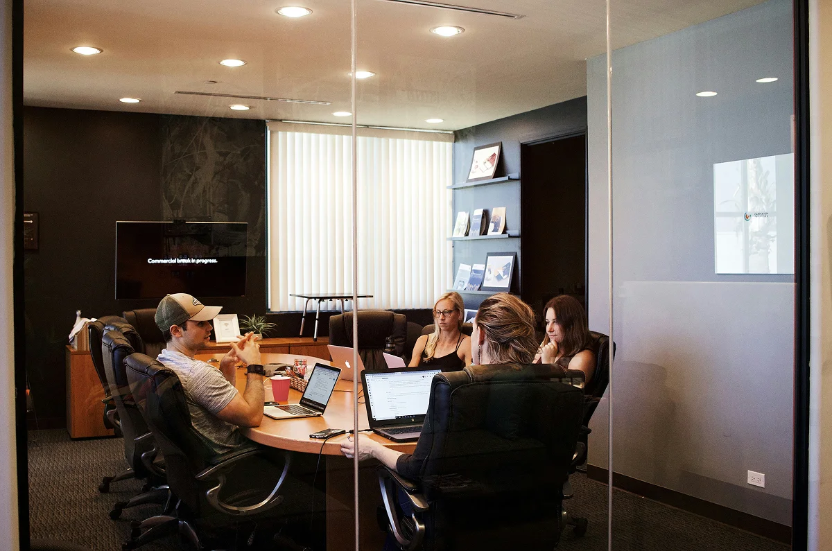 Marketing team in a glass conference room reviewing CRM strategy