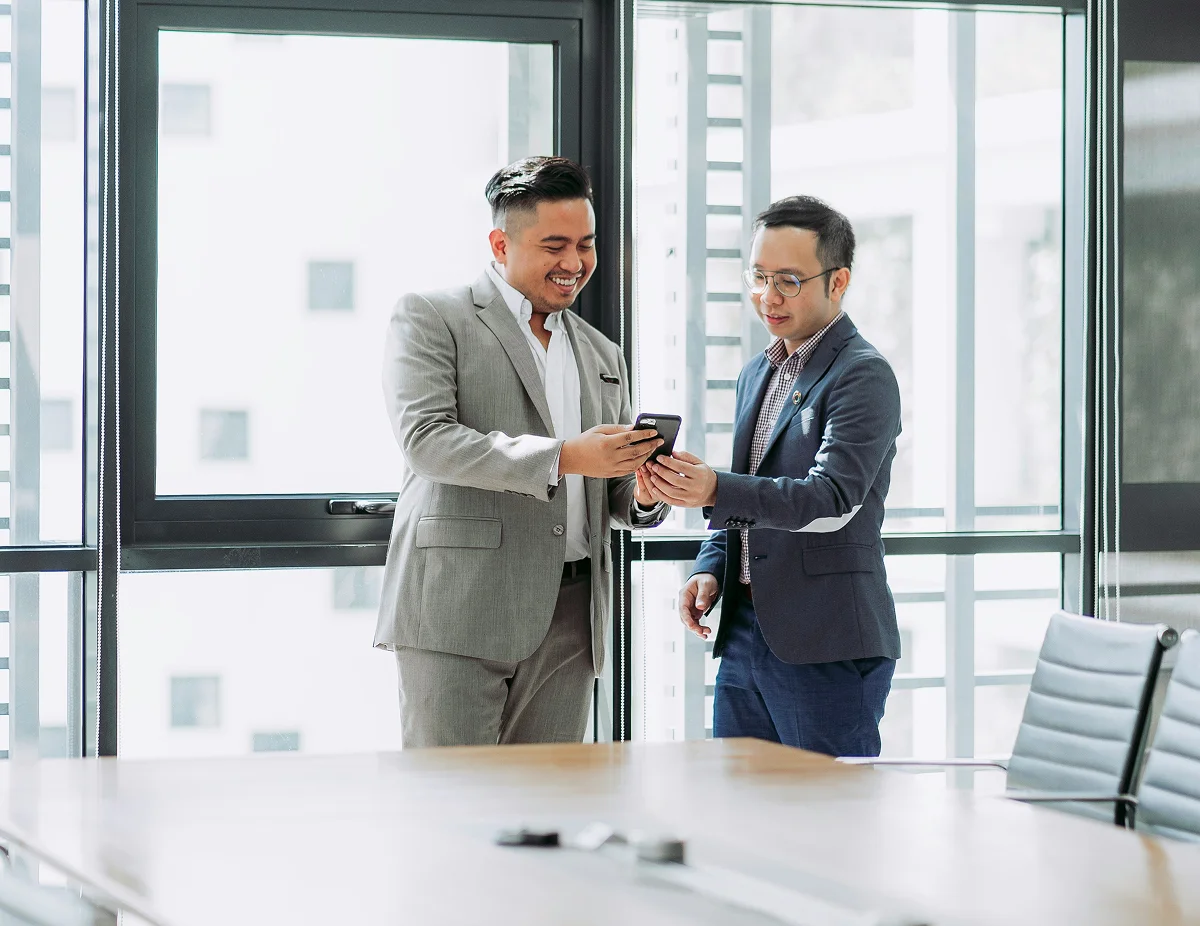 Two business executives reviewing marketing ROI data on a phone