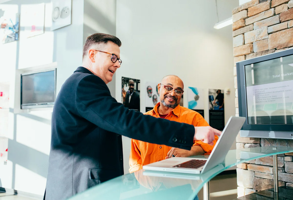 Two B2B executives reviewing thought leadership content on a laptop